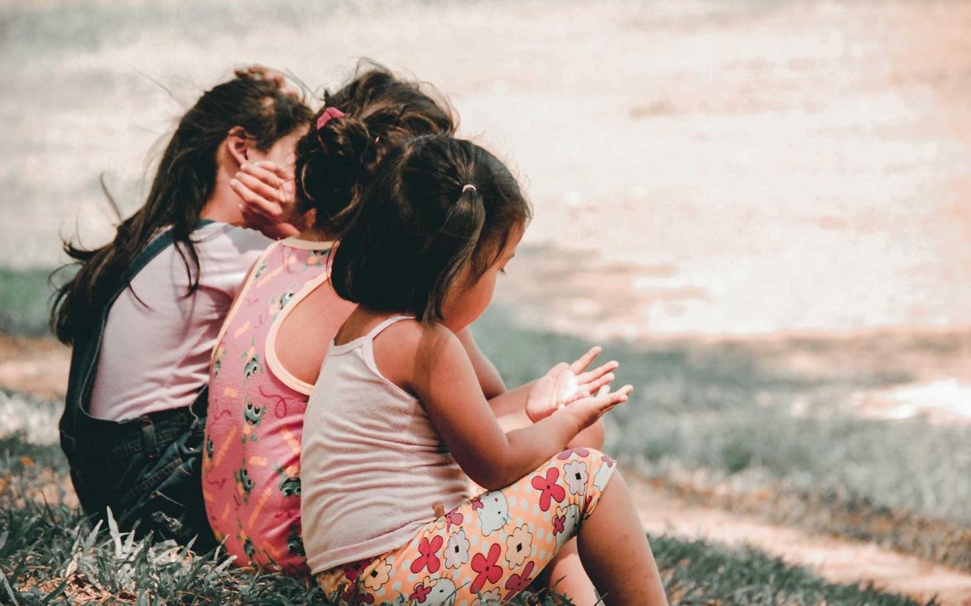 Children sitting on a bench together.